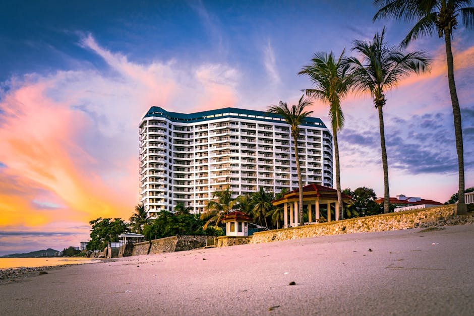 Stunning view of a beachfront resort with palm trees silhouetted against a vibrant sunset.
